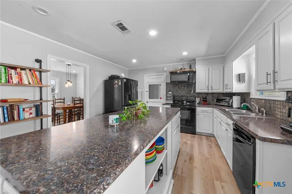a kitchen with stainless steel appliances granite countertop a refrigerator a stove top oven a sink and a island