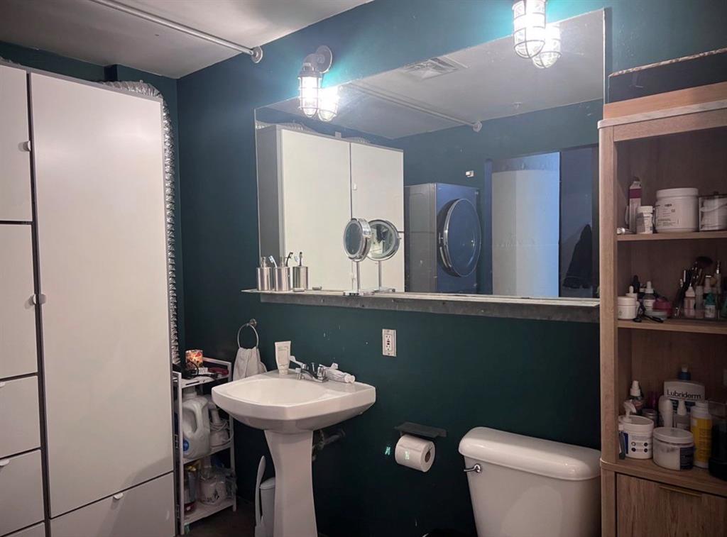 1122 Jackson Street, Unit 514 Dallas, TX 75202 - Photo 28 of 40 Pedestal sink with white ceramic basin, dark green walls, and overhead industrial-style lighting