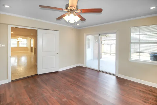 an empty room with wooden floor chandelier fan and windows
