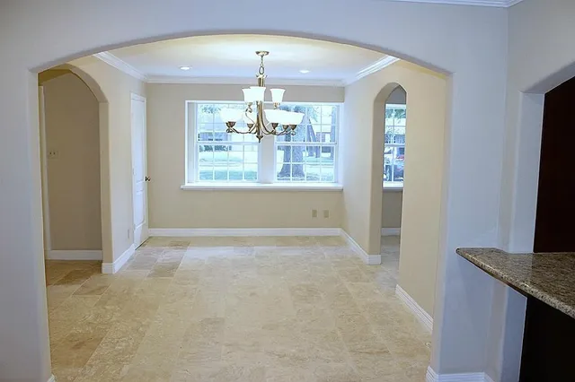 an empty room with chandelier fan and windows