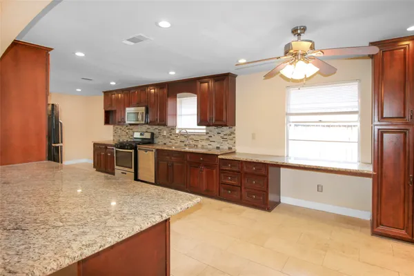 a kitchen with stainless steel appliances granite countertop a sink a stove and a refrigerator