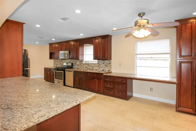 a kitchen with stainless steel appliances granite countertop a sink a stove and a refrigerator