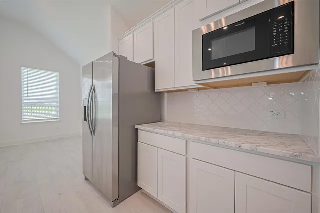 a kitchen with stainless steel appliances white cabinets and a refrigerator