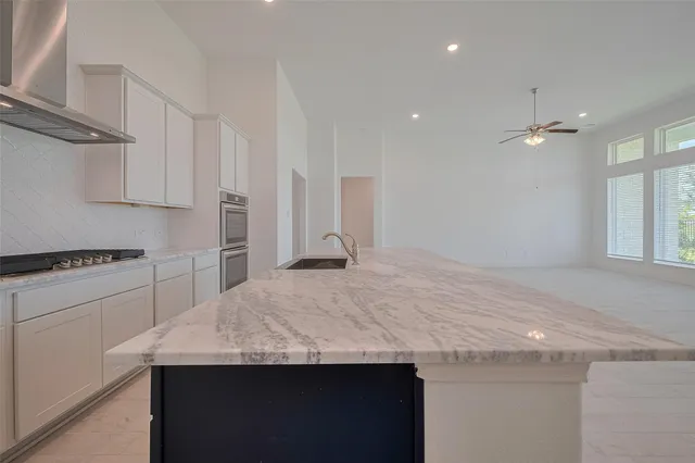 a kitchen with granite countertop a sink a stove a refrigerator and white cabinets