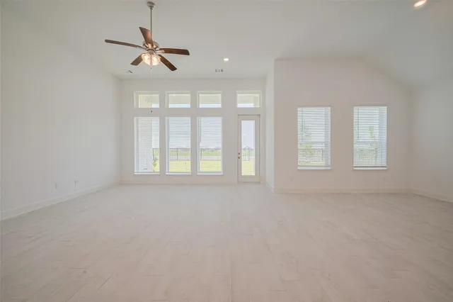 an empty room with windows and fan