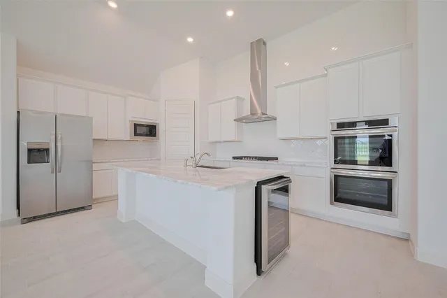 a kitchen with stainless steel appliances kitchen island granite countertop a refrigerator a sink and a stove