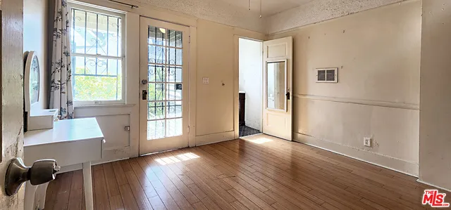a view of an empty room with a window and wooden floor