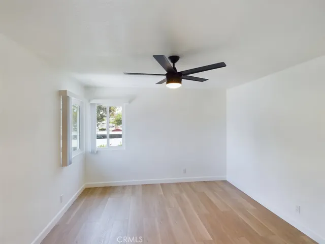 an empty room with windows and ceiling fan