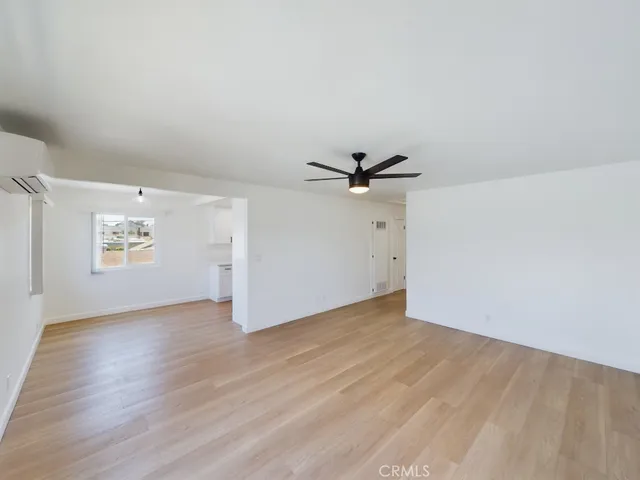 an empty room with wooden floor closet and windows