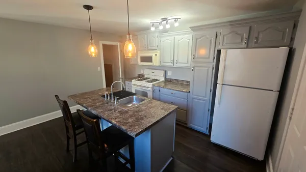 a kitchen with refrigerator and wooden floor