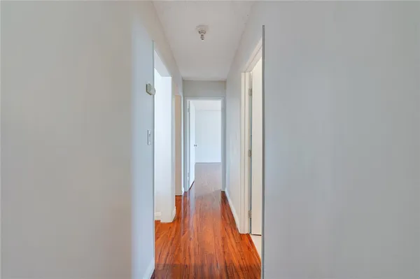 a view of a hallway with wooden floor and a bathroom