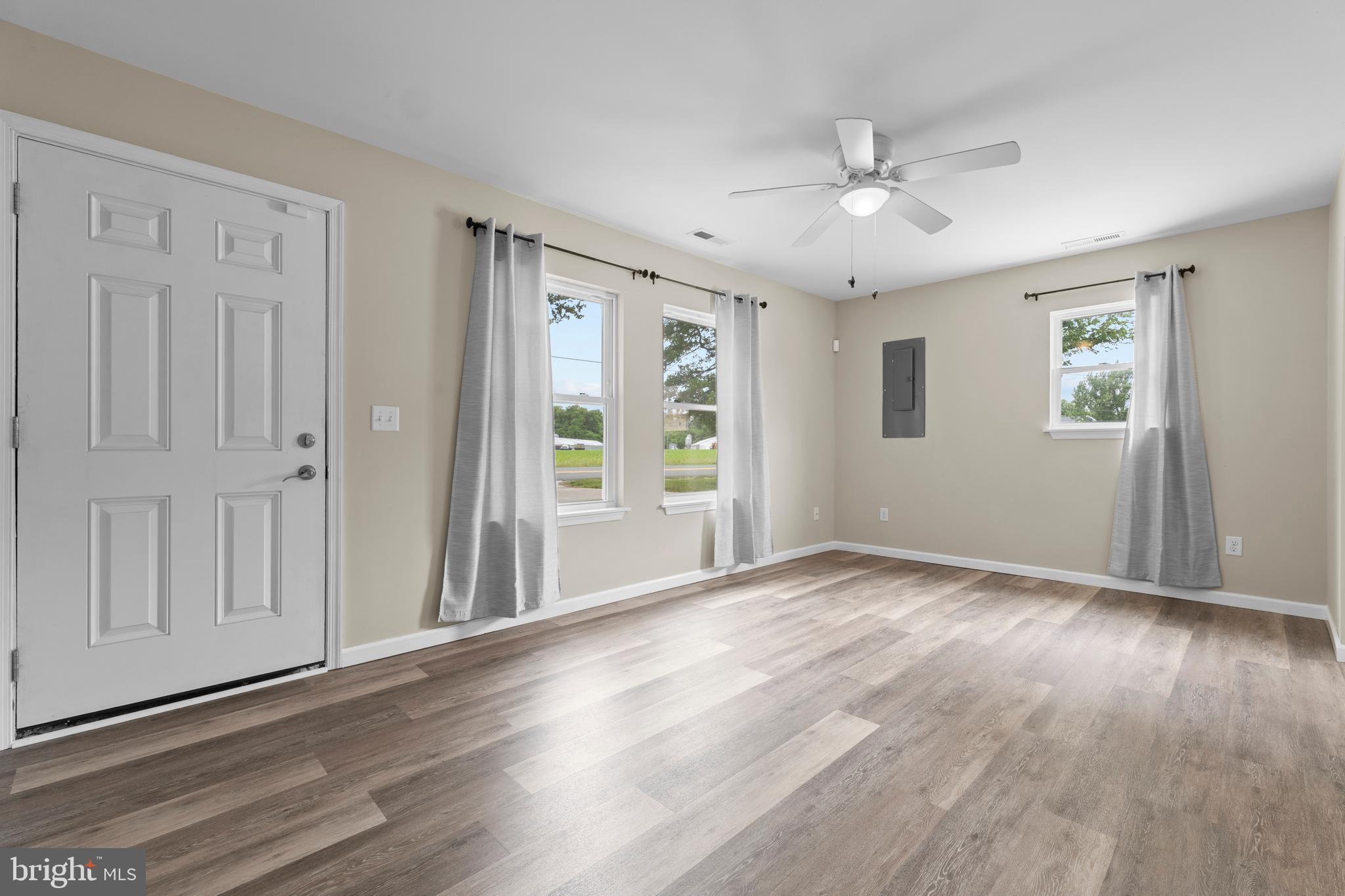 6475 Big Stone Beach Road Milford, DE 19963 - Photo 3 of 52 an empty room with wooden floor chandelier fan and windows