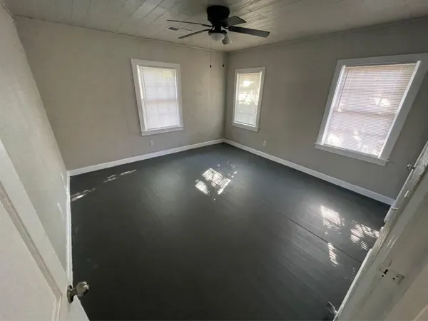a view of an empty room with a window and wooden floor