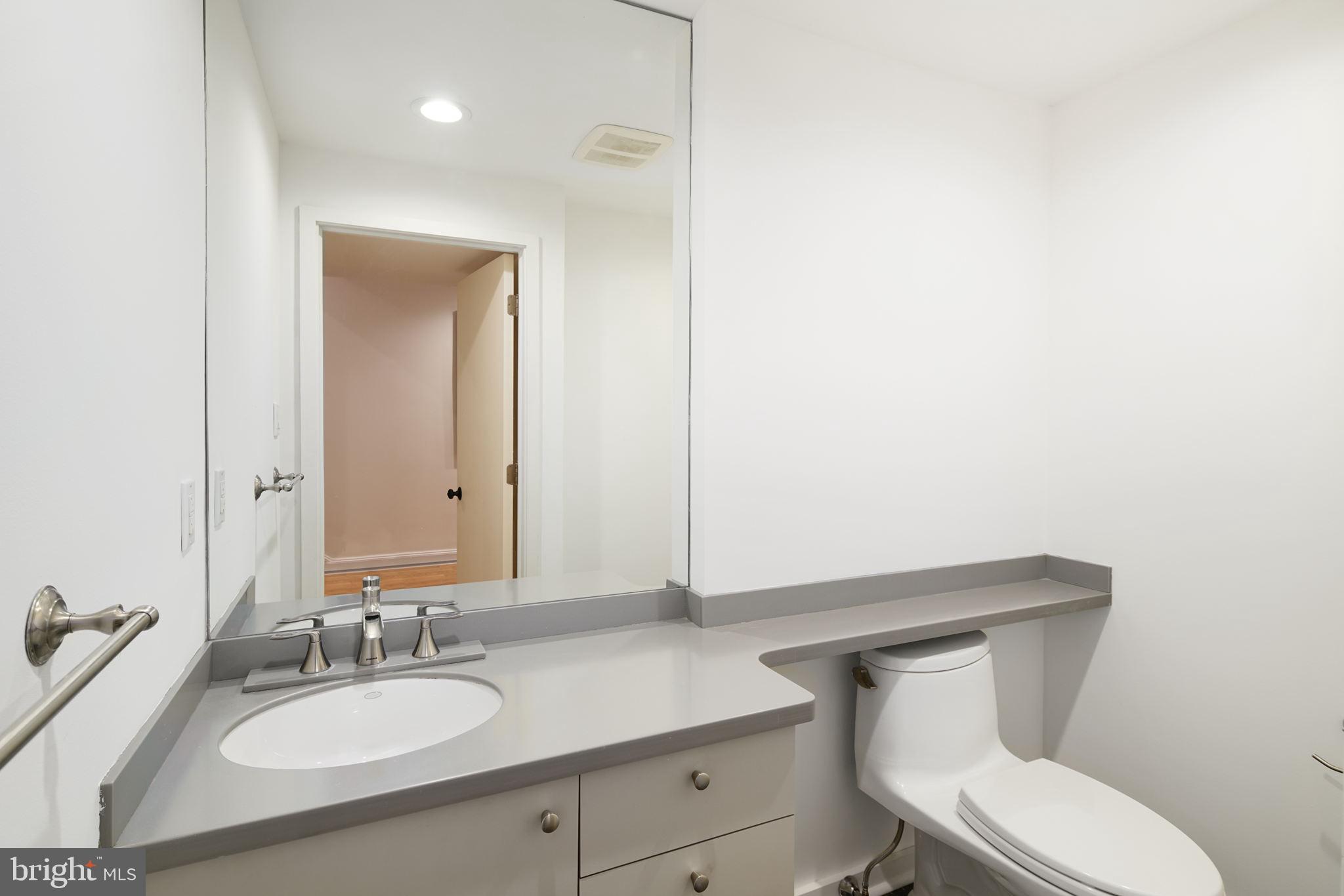 2028 Locust Street Philadelphia, PA 19103 - Photo 11 of 31 a bathroom with a granite countertop toilet sink mirror and vanity