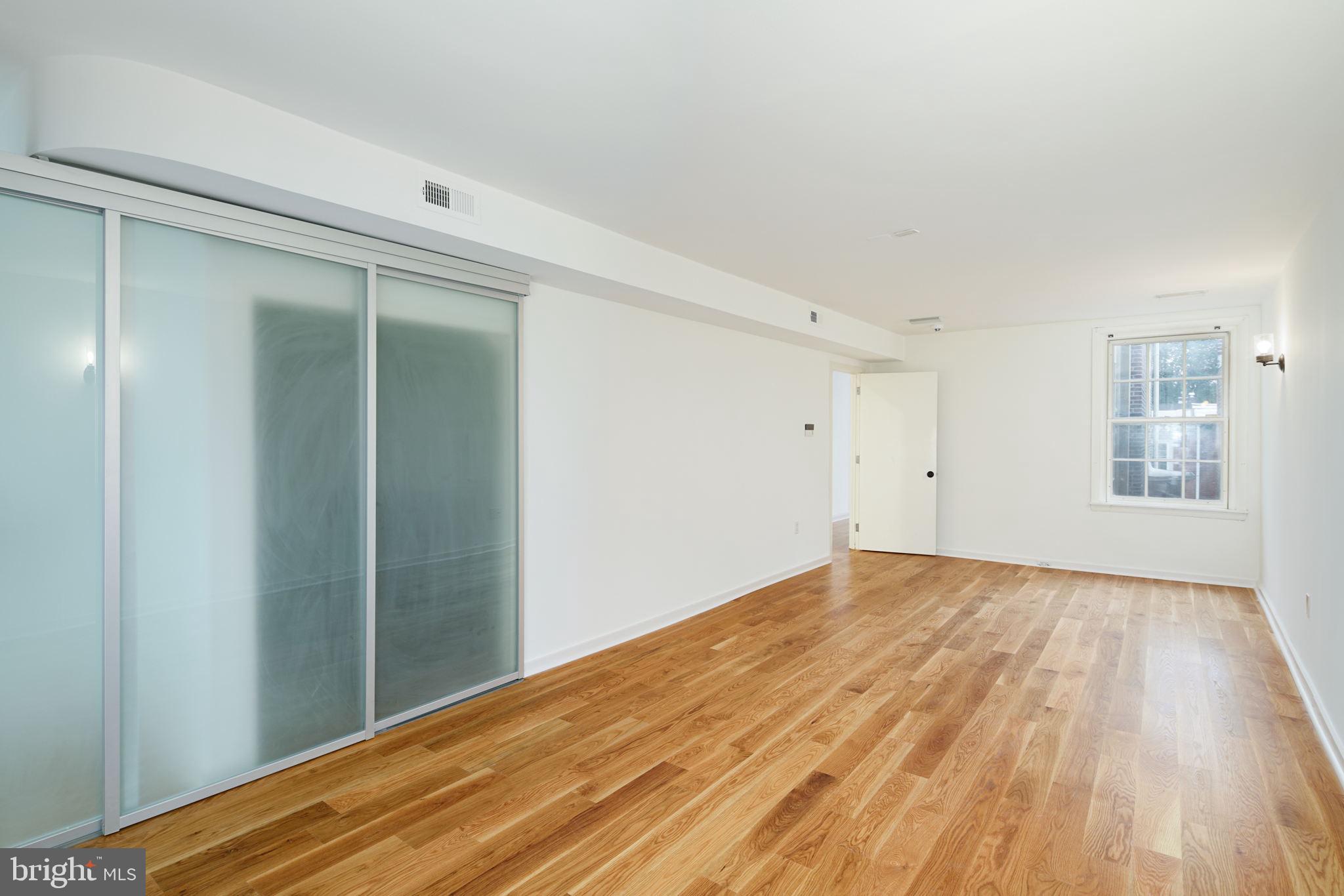 2028 Locust Street Philadelphia, PA 19103 - Photo 21 of 31 a view of an empty room with wooden floor and a window