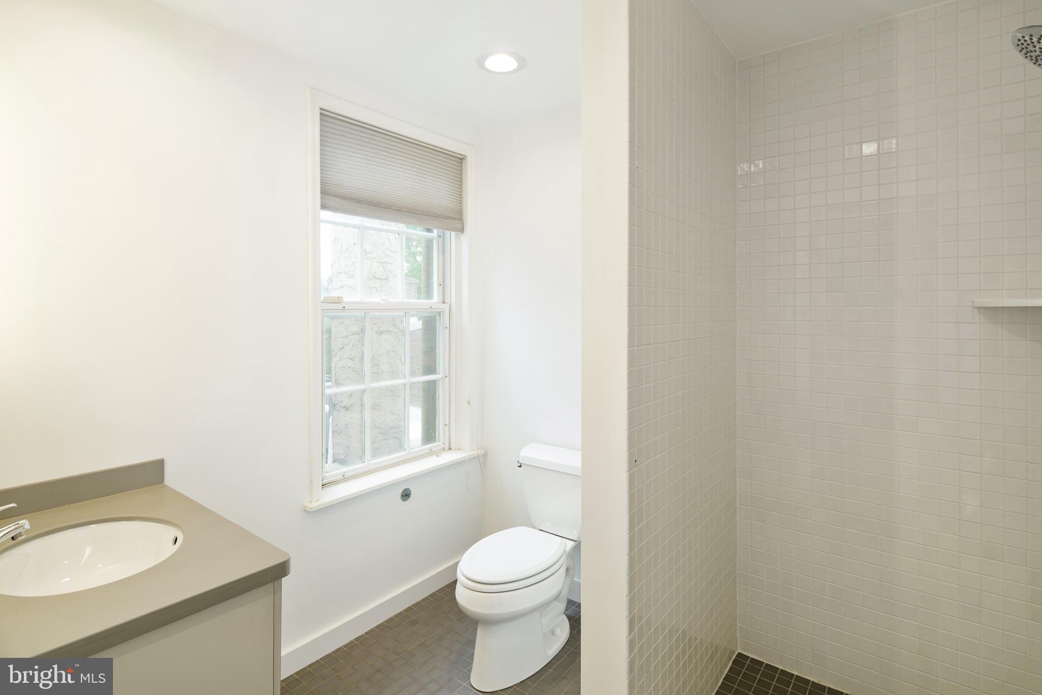 2028 Locust Street Philadelphia, PA 19103 - Photo 26 of 31 a bathroom with a granite countertop toilet a sink a mirror and a window