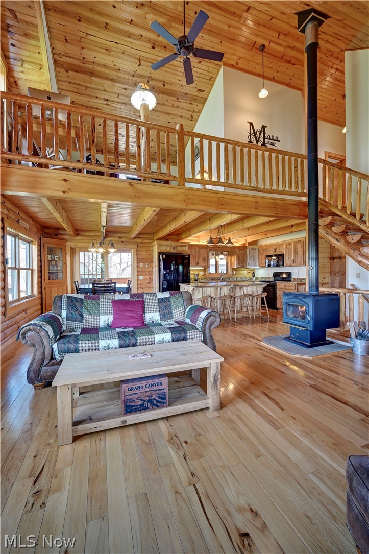 8045 McFadden Road Shreve, OH 44676 - Photo 26 of 45 Living room with a high wood ceiling, a wood stove, a ceiling fan, light wood-style flooring, and wooden walls