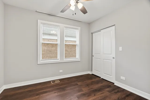 an empty room with wooden floor chandelier and windows