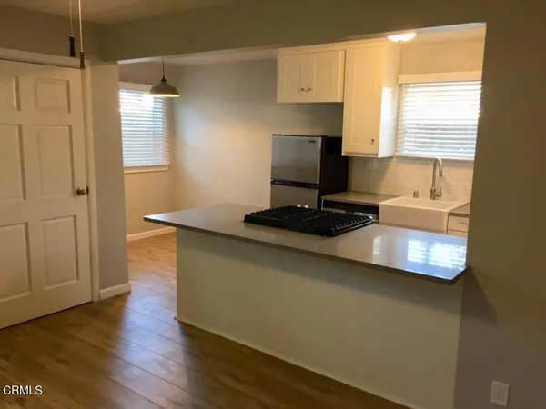 a kitchen with kitchen island granite countertop a sink cabinets and a wooden floor