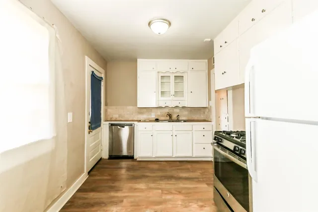 a kitchen with granite countertop a refrigerator stove top oven and sink