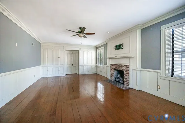 a view of a livingroom with a fireplace a ceiling fan and windows
