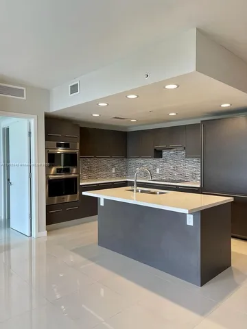 a large kitchen with stainless steel appliances a large counter top
