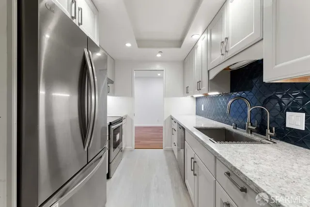 a kitchen with stainless steel appliances granite countertop a sink a stove and a refrigerator