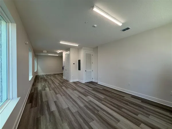 an empty room with wooden floor and windows