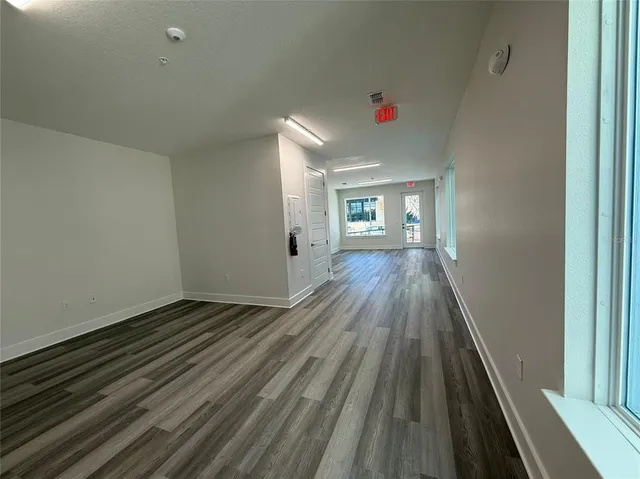 a view of an empty room with a window and wooden floor