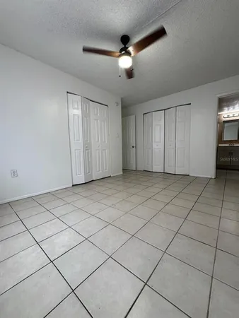 a view of an empty room and chandelier fan