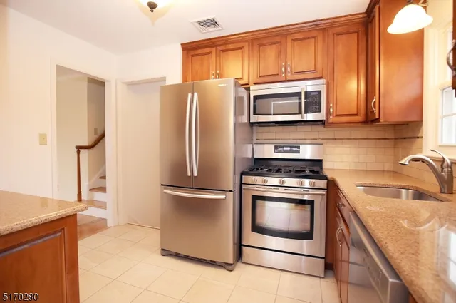 a kitchen with stainless steel appliances granite countertop a refrigerator stove and sink