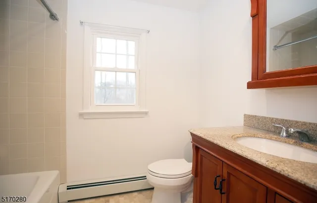 a bathroom with a granite countertop toilet sink and mirror