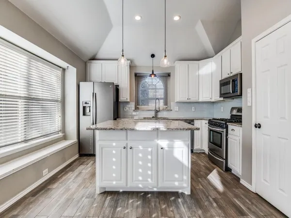 a kitchen with stainless steel appliances granite countertop a stove a sink and a refrigerator