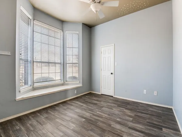 a view of an empty room with window and wooden floor