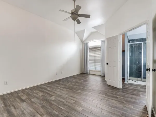 an empty room with wooden floor and a ceiling fan