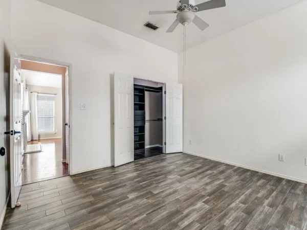 a view of an empty room with a window and wooden floor