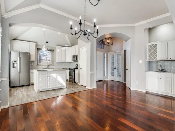 a view of a kitchen with granite countertop wooden floor stainless steel appliances and a chandelier