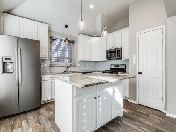 a kitchen with kitchen island granite countertop a sink stainless steel appliances and cabinets