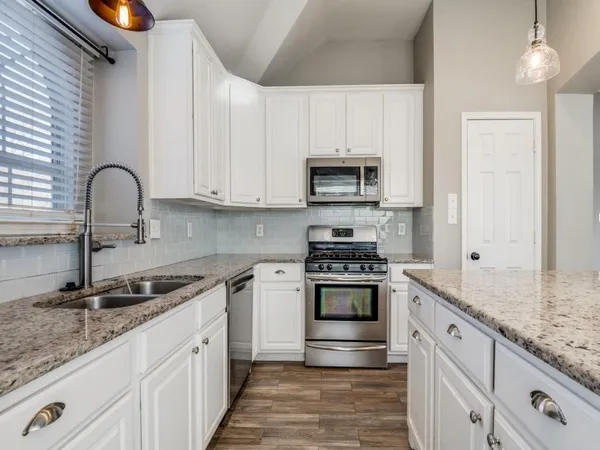 a kitchen with stainless steel appliances granite countertop a sink stove and cabinets