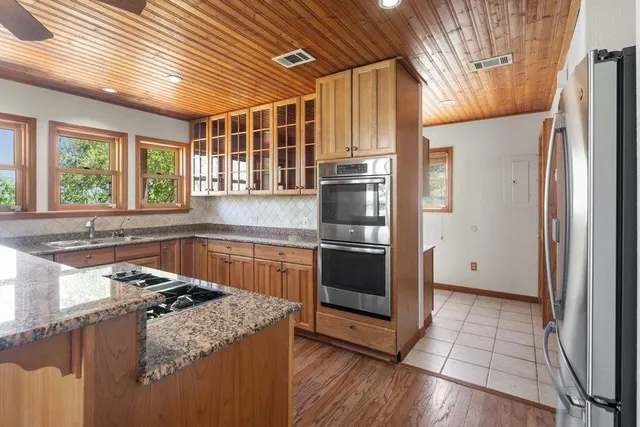 a kitchen with granite countertop a sink stainless steel appliances and cabinets