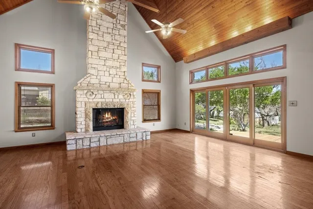 a view of an empty room with wooden floor and a fireplace