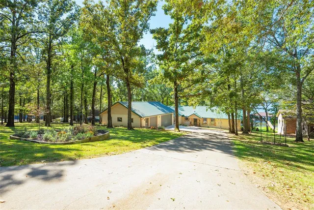 a view of a house with a big yard and large trees