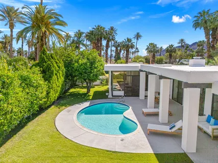a view of swimming pool with seating area and trees in the background