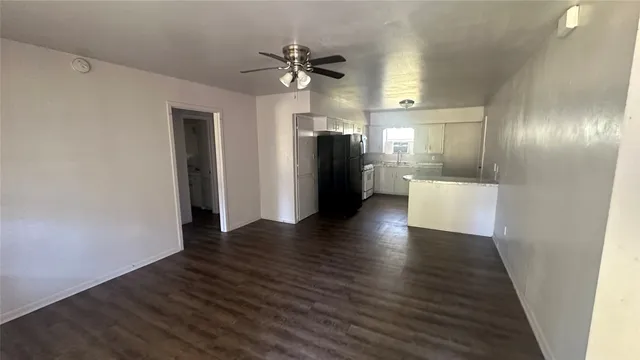 a view of a hallway with wooden floor and a kitchen