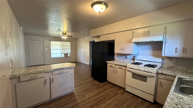 a kitchen with cabinets appliances and wooden floor
