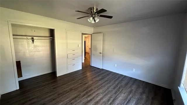 an empty room with wooden floor and a ceiling fan