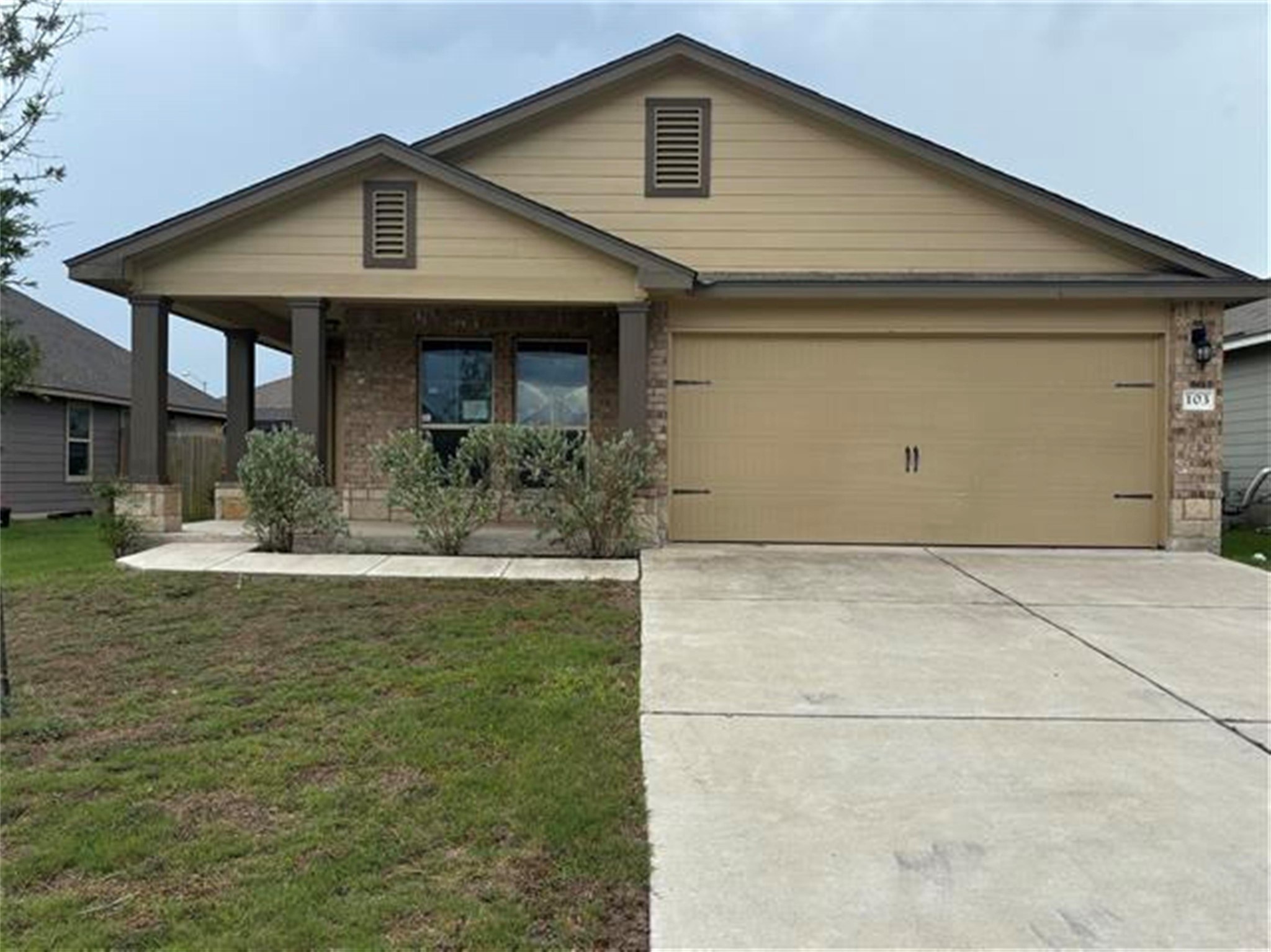 103 Beth Ann Loop Taylor, TX 76574 - Photo 1 of 1 View of front of home featuring a porch, an attached garage, a front yard, driveway, and brick siding