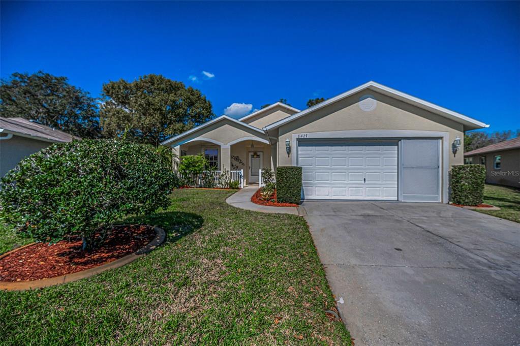 11427 Turtle Dove Place New Port Richey, FL 34654 - Photo 4 of 100 a front view of a house with a yard and garage