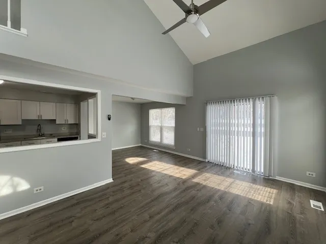 an empty room with wooden floor and a kitchen