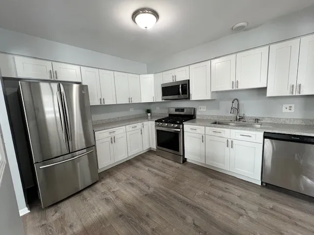 a kitchen with white cabinets stainless steel appliances and a refrigerator